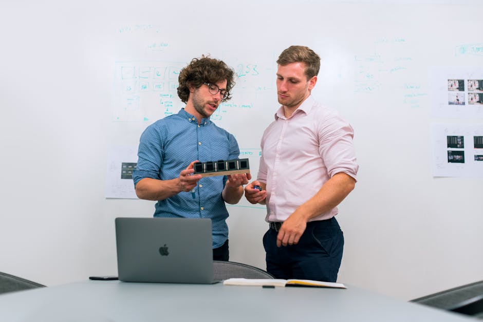 Two men in an office discussing and reviewing a tech prototype