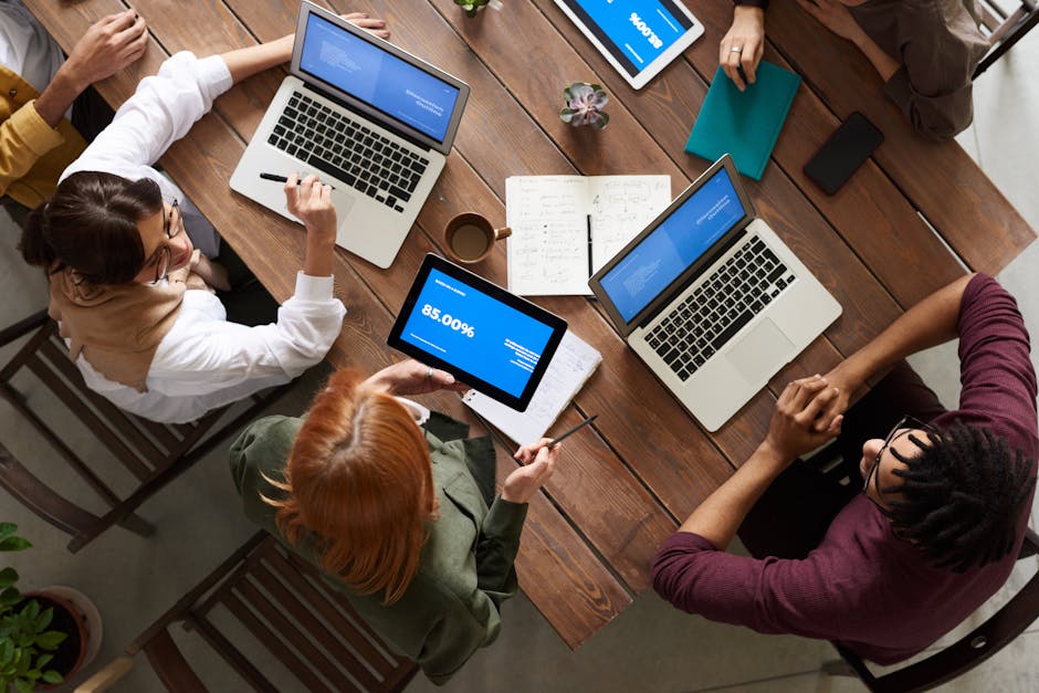 Diverse team discussing business strategies with laptops and tablets at a wooden table