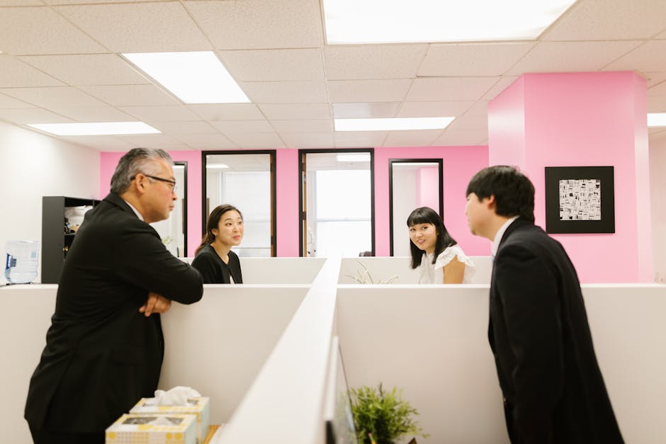 A group of Asian colleagues engaged in a lively discussion in a modern office setting